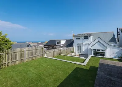 a backyard with a fence and a yard with green grass at Tregenna, Port Isaac Bay Holiday in Port Isaac
