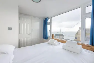a bedroom with a large white bed and a large window at Tregenna, Port Isaac Bay Holiday in Port Isaac