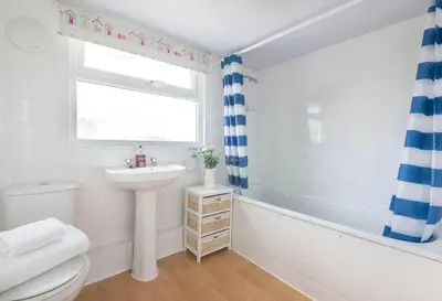 a bathroom with a sink and a toilet and a window at Tregenna, Port Isaac Bay Holiday in Port Isaac
