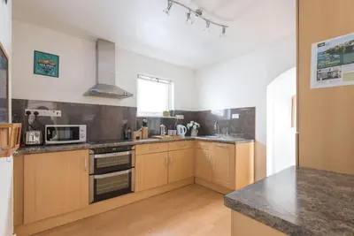 a kitchen with wooden cabinets and a counter top at Tregenna, Port Isaac Bay Holiday in Port Isaac