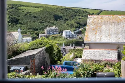 a blue truck parked in front of a house with flowers at Gulls Roost, Port Isaac Bay Holidays in Port Isaac