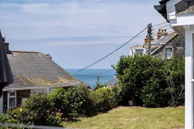 a couple of houses with the ocean in the background at Gulls Roost, Port Isaac Bay Holidays in Port Isaac