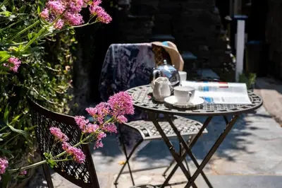 a glass table with a tea kettle on it next to a chair at Gulls Roost, Port Isaac Bay Holidays in Port Isaac