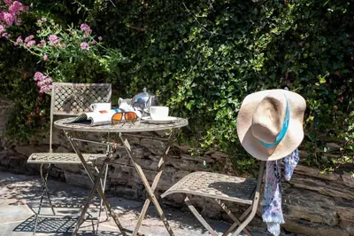 a table with a hat sitting next to a chair at Gulls Roost, Port Isaac Bay Holidays in Port Isaac