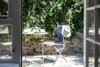 a table and a chair with a hat on a patio at Gulls Roost, Port Isaac Bay Holidays in Port Isaac