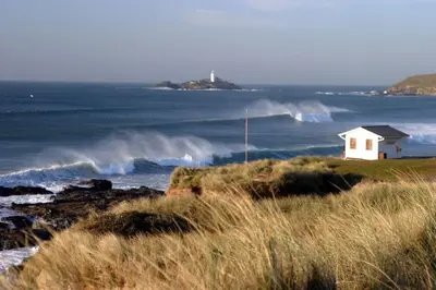 a small white house on the shore of a body of water at Family friendly home by the beach in Hayle