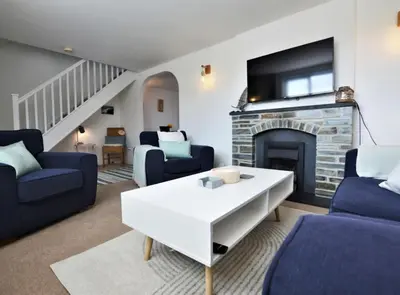a living room with blue furniture and a fireplace at Family friendly home by the beach in Hayle