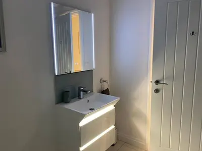 a white bathroom with a sink and a mirror at The Emslie Road Beach Flat in Falmouth