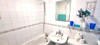 a white tiled bathroom with a sink and a bath tub at 9 Wheal Ramoth in Perranporth