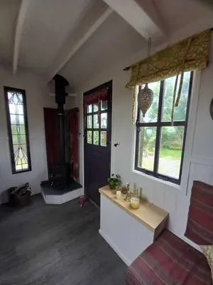 a living room with a room with a door and windows at Field Hut in Wadebridge