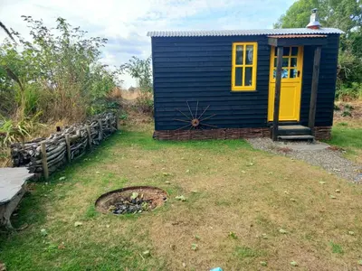 a blue house with a yellow door in a yard at Field Hut in Wadebridge