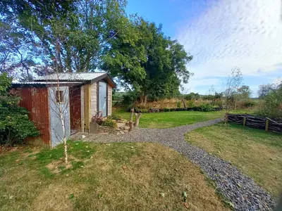 a garden with a small shed and a tree at Field Hut in Wadebridge
