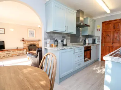 a kitchen with white cabinets and a table in a room at Salakee in Penzance
