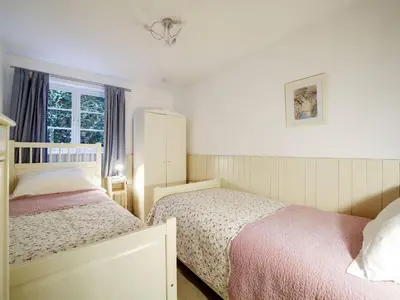 a small bedroom with two beds and a window at Bosuns Locker in Port Isaac