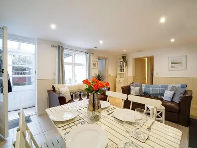a living room with a table with a vase of flowers at Bosuns Locker in Port Isaac