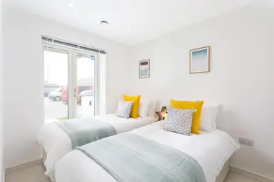 two beds in a white room with a window at Luxury 3 floor Town House by Tolcarne Beach in Newquay