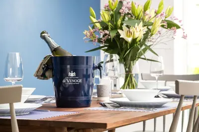 a bottle of champagne in a bucket on a table with flowers at Luxury 3 floor Town House by Tolcarne Beach in Newquay