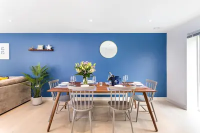 a dining room with a blue wall and a table and chairs at Luxury 3 floor Town House by Tolcarne Beach in Newquay