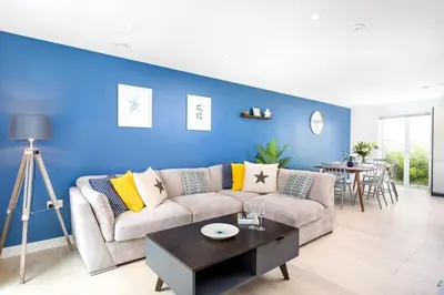 a living room with a couch and a blue wall at Luxury 3 floor Town House by Tolcarne Beach in Newquay