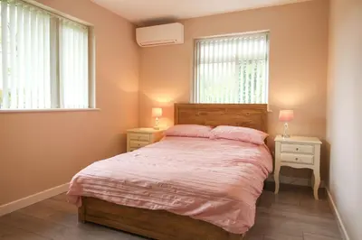 a bedroom with a bed with two night stands and two windows at Gwel An Koos in Bodmin