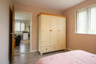 a bedroom with a white cabinet and a living room at Gwel An Koos in Bodmin