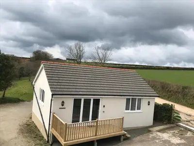 a small white shed with a porch in a field at Gwel An Koos in Bodmin