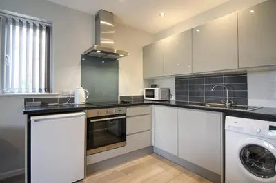 a kitchen with white cabinets and a washer and dryer at Gwel An Koos in Bodmin