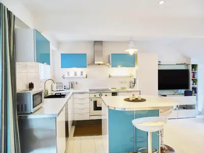 a kitchen with blue and white cabinets and a table at The Mermaid Loft - Trebarwith Strand Cornwall in Tintagel