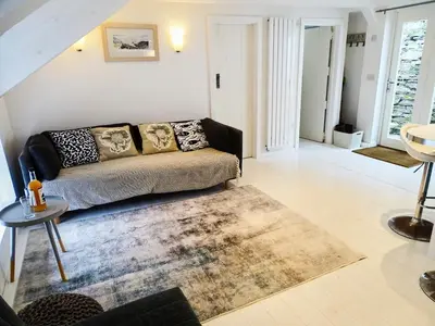 a living room with a couch and a rug at The Mermaid Loft - Trebarwith Strand Cornwall in Tintagel