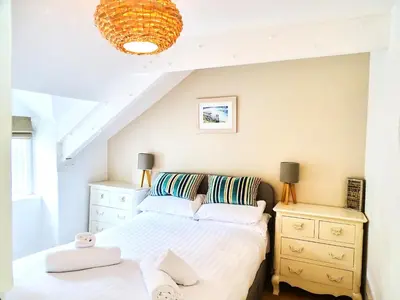 a bedroom with a bed and a dresser at The Mermaid Loft - Trebarwith Strand Cornwall in Tintagel