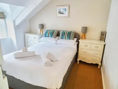 a small bedroom with a bed and a night stand at The Mermaid Loft - Trebarwith Strand Cornwall in Tintagel