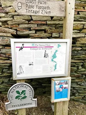a sign in front of a stone wall at The Mermaid Loft - Trebarwith Strand Cornwall in Tintagel
