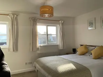 a bedroom with a bed and two windows at Newly Renovated 2 Bed house nr Fistral Beach & Gannel Estuary in Newquay