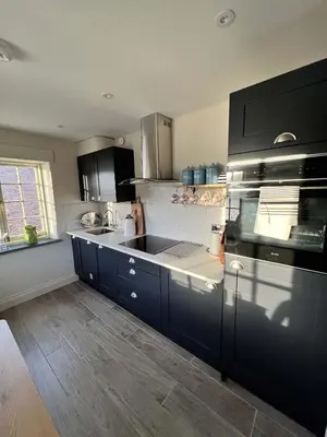 a kitchen with dark blue cabinets and a stove top oven at Oystercatcher in Fowey