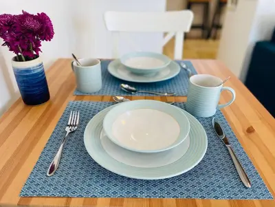 a wooden table with plates and cups and utensils at Cosy Rustic Annex in quiet Cornwall Village in Saint Wenn