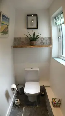 a bathroom with a white toilet and a window at Cosy Rustic Annex in quiet Cornwall Village in Saint Wenn