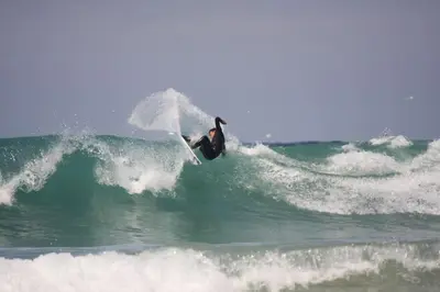a person riding a wave on a surfboard in the ocean at Cosy Rustic Annex in quiet Cornwall Village in Saint Wenn