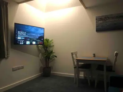 a dining room with a table and a tv on the wall at Cosy Rustic Annex in quiet Cornwall Village in Saint Wenn