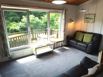 a living room with a couch and a large window at Rusey Cottage at Crackington Haven, near Bude and Boscastle, Cornwall in Bude