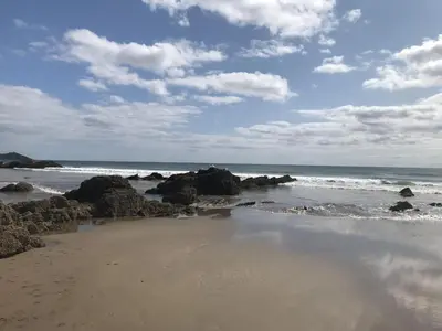a beach with rocks and the ocean on a cloudy day at Corn Barn at East Trenean Farm -Luxury Cornish Barn Conversion sleeping 8 with hot tub, private garden, rural views and EV facilities in Looe