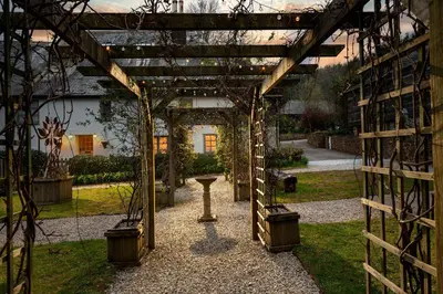 a wooden pergola with a table in a garden at Corn Barn at East Trenean Farm -Luxury Cornish Barn Conversion sleeping 8 with hot tub, private garden, rural views and EV facilities in Looe