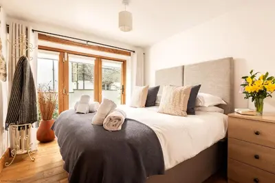 a bedroom with a large bed and a window at Corn Barn at East Trenean Farm -Luxury Cornish Barn Conversion sleeping 8 with hot tub, private garden, rural views and EV facilities in Looe