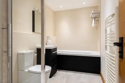 a bathroom with a toilet and a sink and a tub at Corn Barn at East Trenean Farm -Luxury Cornish Barn Conversion sleeping 8 with hot tub, private garden, rural views and EV facilities in Looe