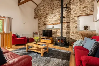 a living room with red furniture and a brick wall at East Trenean Farm Cottages -4 Luxury Cornish Cottages sleeping 20 with hot tubs, private gardens, rural views and EV facilities in Looe