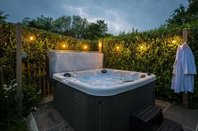a jacuzzi tub in a garden with lights at East Trenean Farm Cottages -4 Luxury Cornish Cottages sleeping 20 with hot tubs, private gardens, rural views and EV facilities in Looe