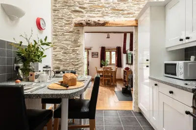 a kitchen and dining room with a table in a kitchen at East Trenean Farm Cottages -4 Luxury Cornish Cottages sleeping 20 with hot tubs, private gardens, rural views and EV facilities in Looe