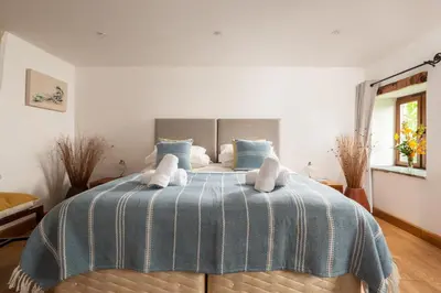 a bedroom with a bed with a blue and white blanket at Water Mill at East Trenean Farm -Luxury Cornish Cottage sleeping 4 with hot tub, private garden, rural views and EV facilities in East Looe