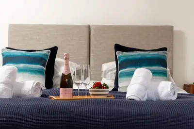 a bed with a bottle of wine and towels and wine glasses at Water Mill at East Trenean Farm -Luxury Cornish Cottage sleeping 4 with hot tub, private garden, rural views and EV facilities in East Looe