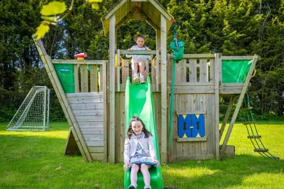 two children playing on a playground with a slide at Water Mill at East Trenean Farm -Luxury Cornish Cottage sleeping 4 with hot tub, private garden, rural views and EV facilities in East Looe