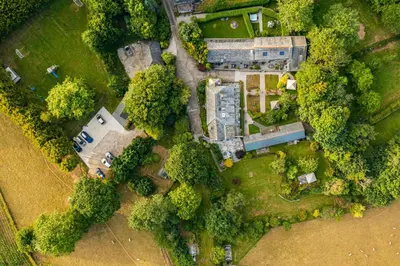an overhead view of a mansion in the midst of trees at Water Mill at East Trenean Farm -Luxury Cornish Cottage sleeping 4 with hot tub, private garden, rural views and EV facilities in East Looe